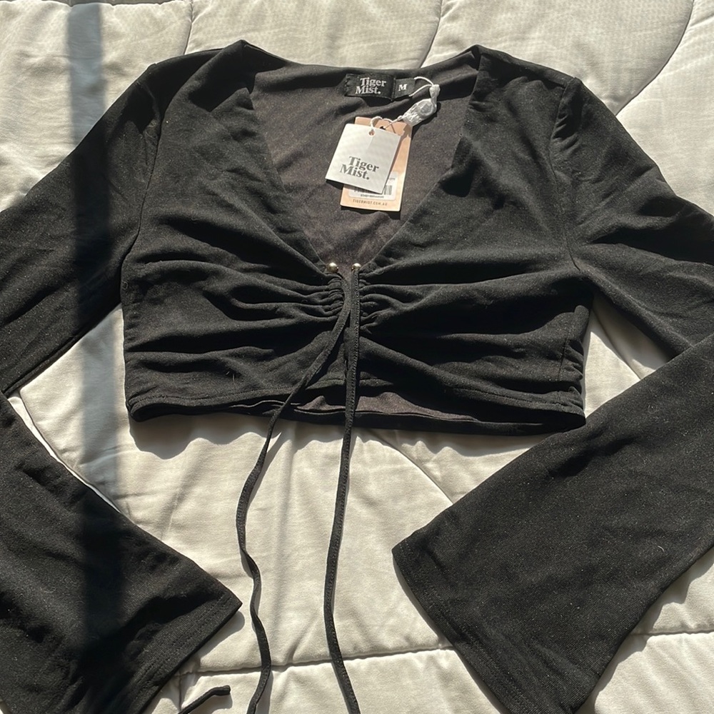 Black cropped, long sleeve shirt with gold detailing.
